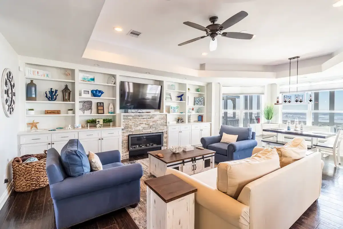 Living room with stone fireplace, built-in shelving, and ocean-view dining nook at Sunrise on the Beach