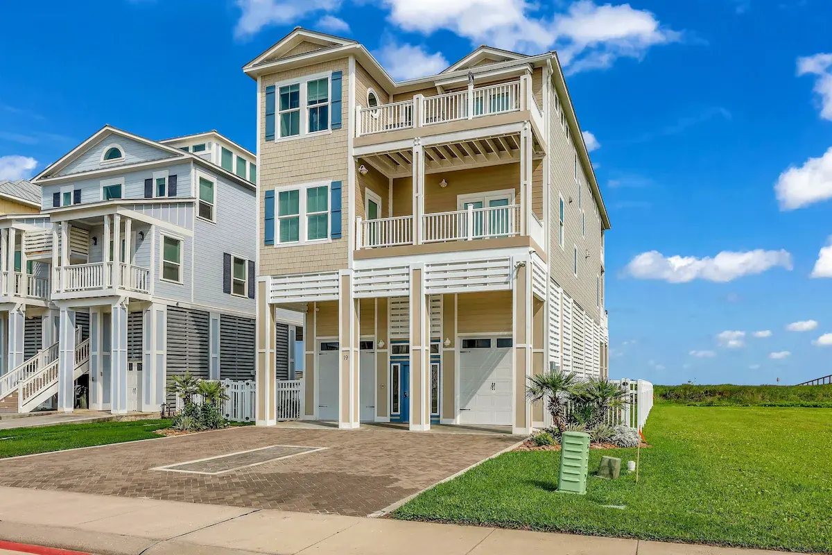 Three-story facade of Sandy Sea-cret with stacked balconies and street-side lawn