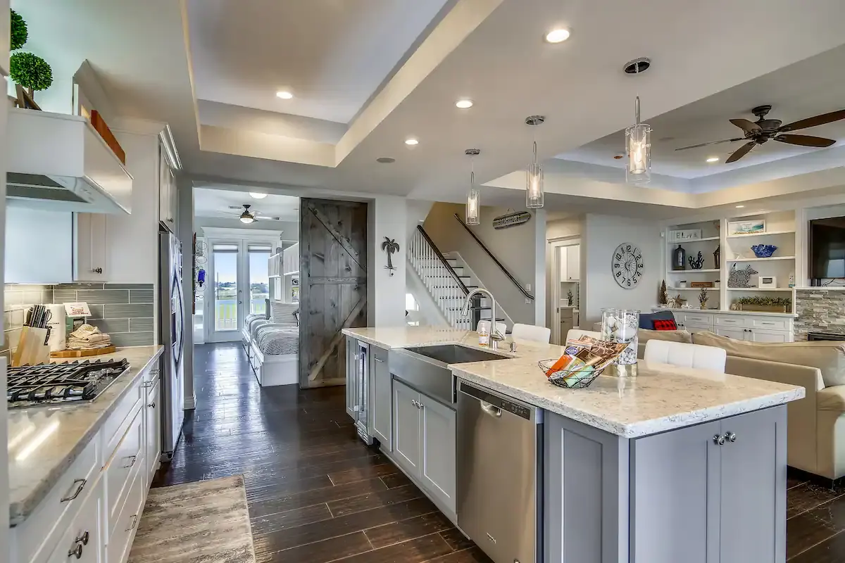 Gourmet kitchen with long quartz island, farmhouse sink, and barn door at Sunrise on the Beach