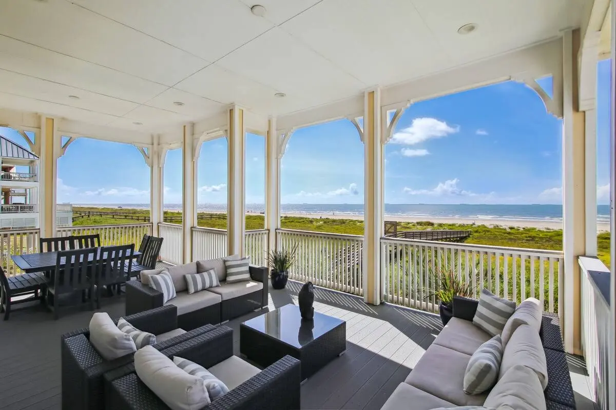 Covered beachfront deck with outdoor sofas and dining table facing the gulf at Dorado Grande