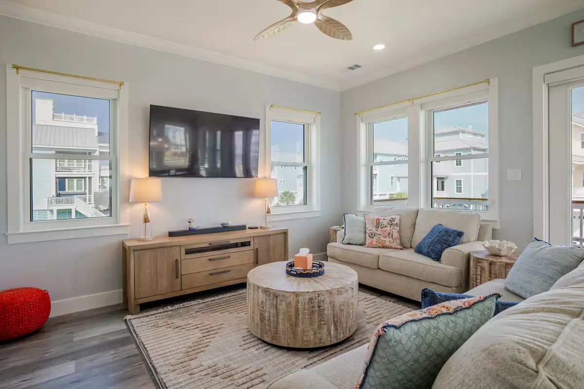 Coastal living room with mounted TV, driftwood coffee table, and neighborhood views at Alma de Mar