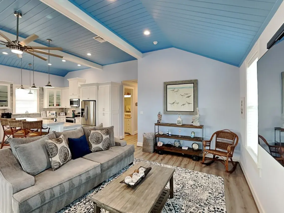 Coastal lounge with wall-mounted TV, rocking chair, and pelican decor at Tiki Retreat