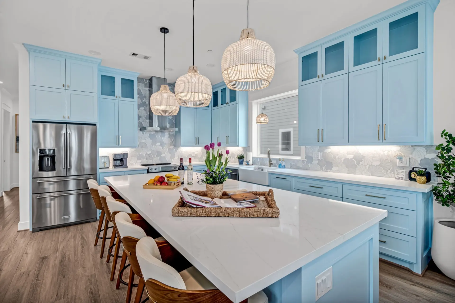 Sky-blue kitchen with long quartz island and woven pendant lights at Grand Beach Retreat